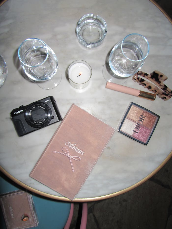 Stylish flat lay of makeup essentials and camera on a marble table for lifestyle inspiration.