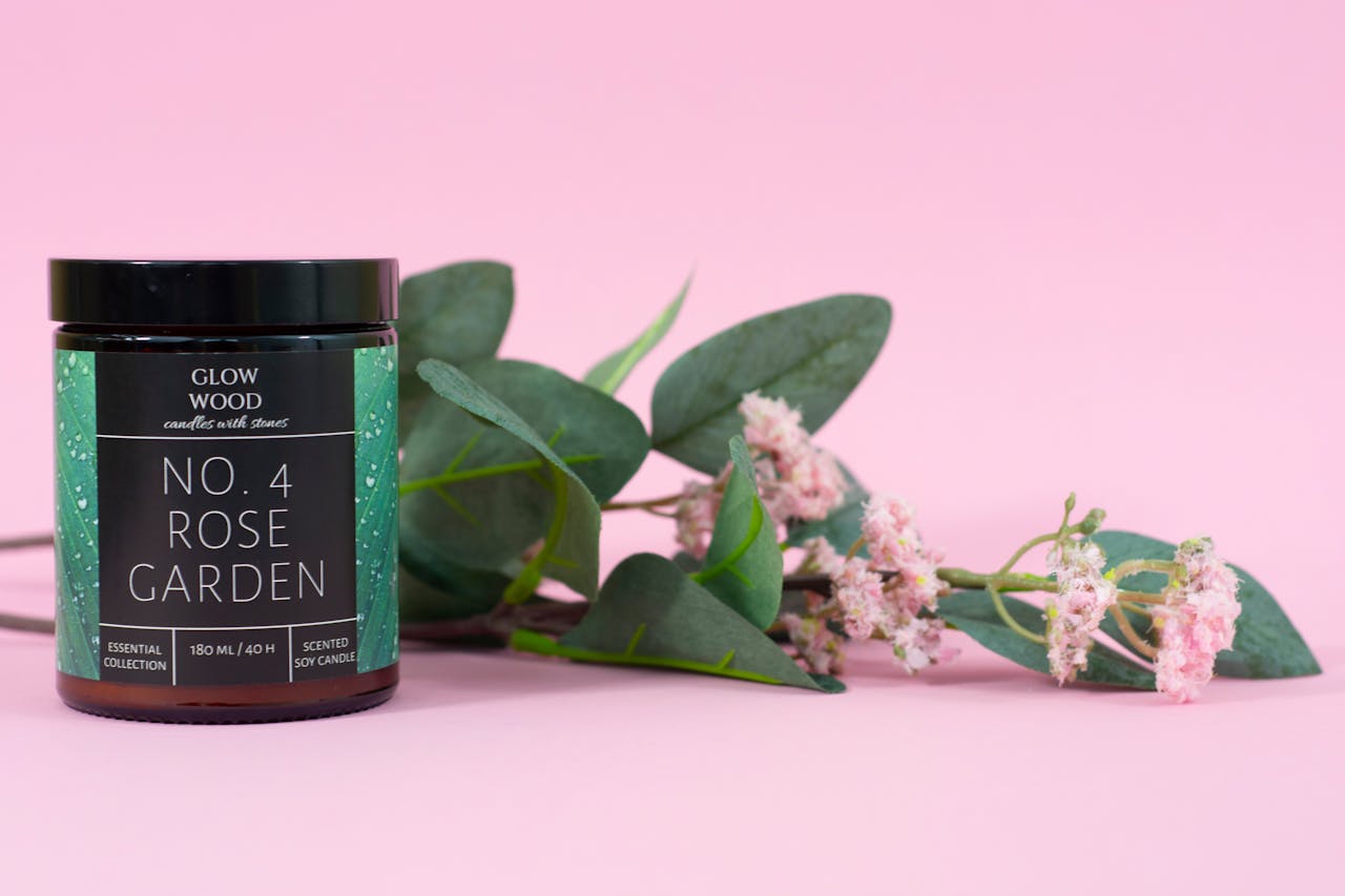 Elegant rose garden scented soy candle with floral decoration on pink background.